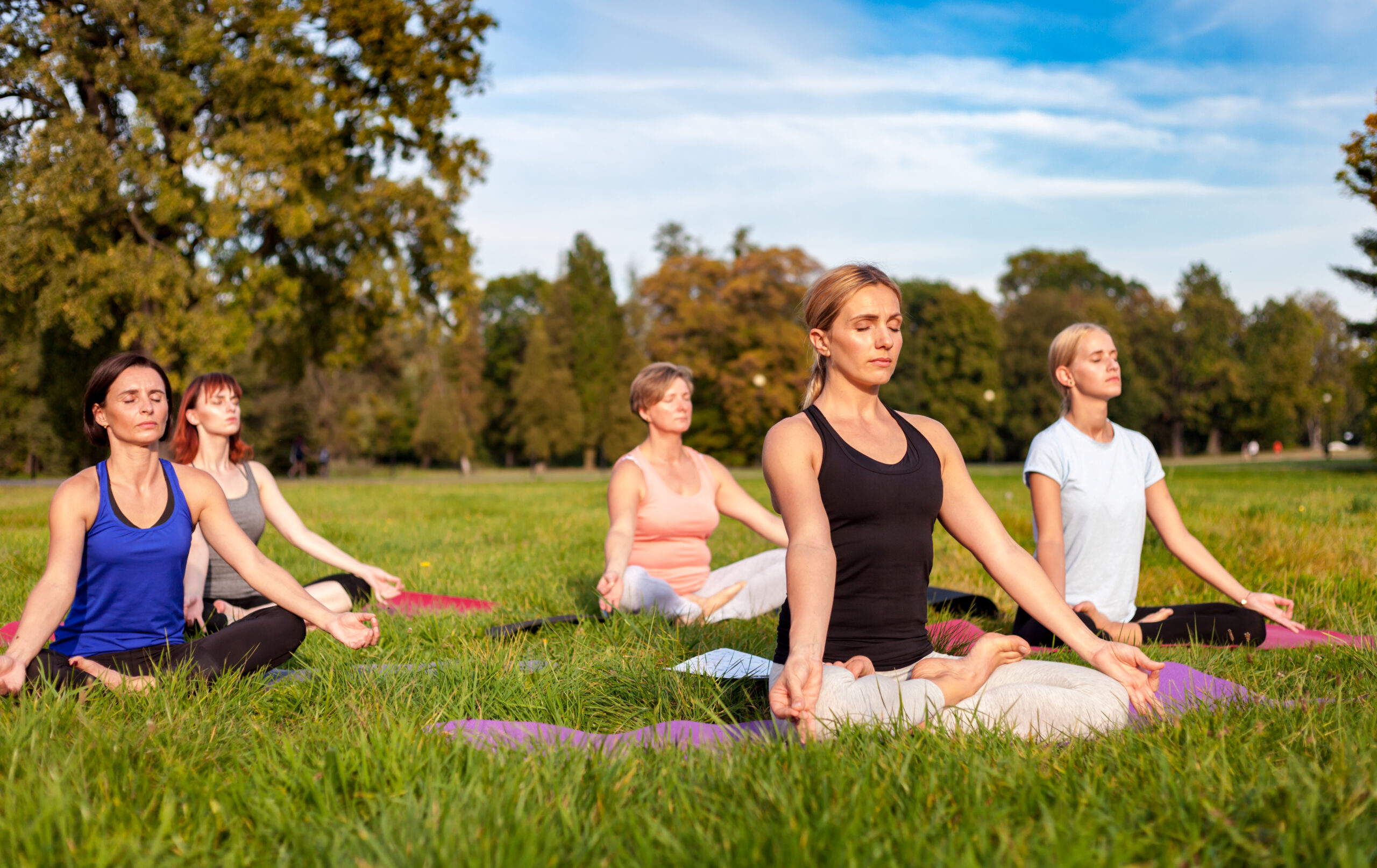 Mixed age group of people practicing yoga outside in the park Mixed age group of people practicing yoga outside in the park